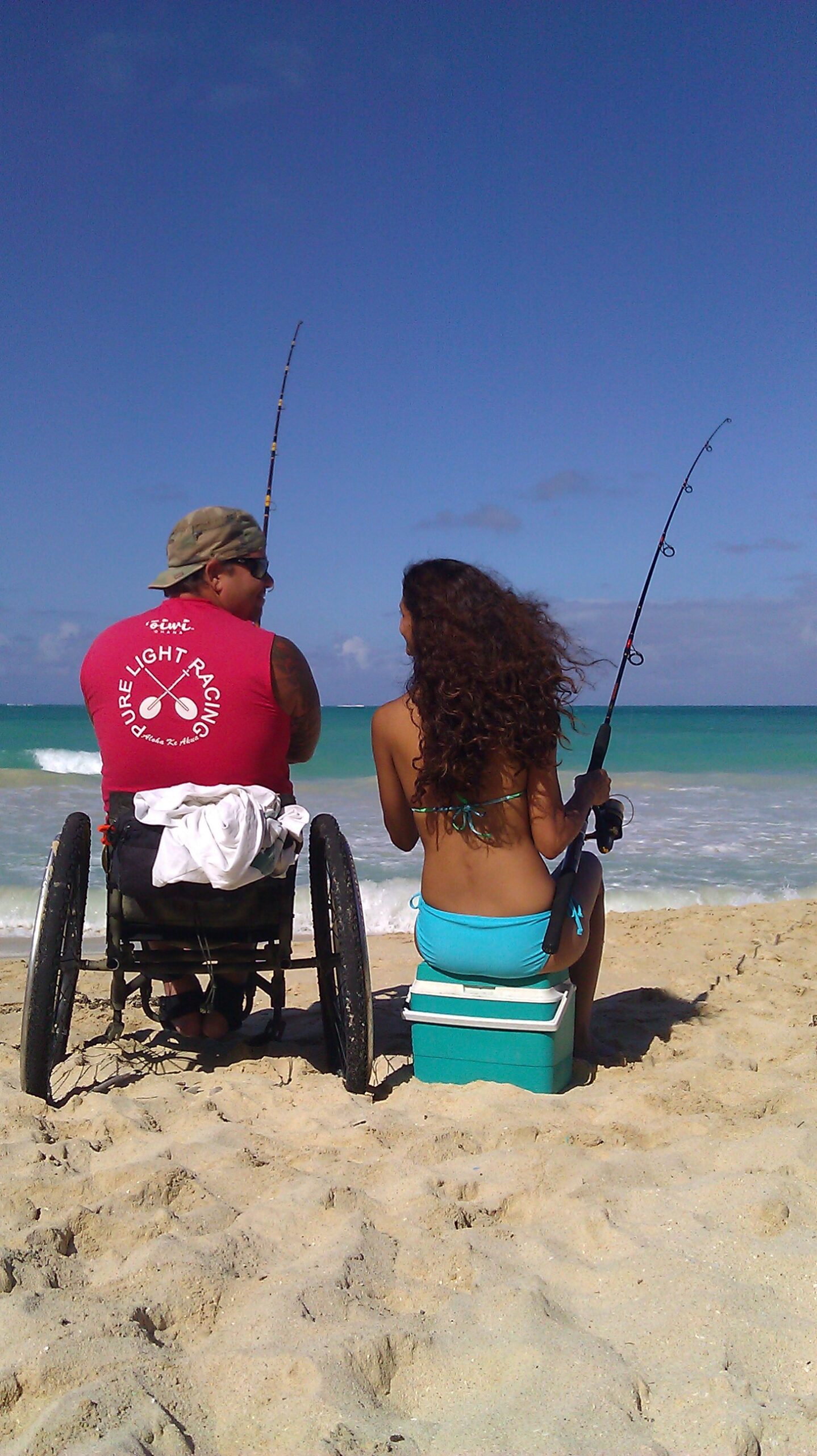 Man in wheelchair fishing by the beach